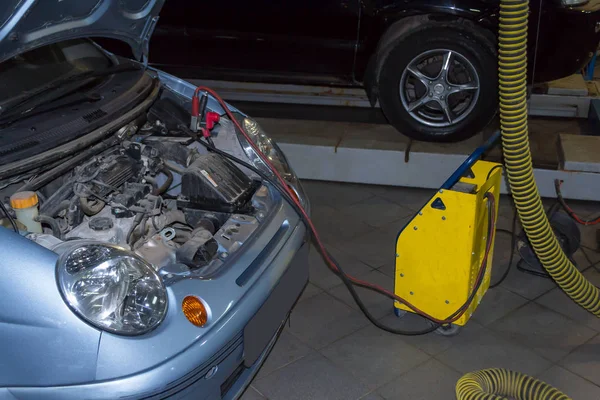 Asansör tamir için bir siyah Suv konumu olan tamir atölyesinde açık bir kukuleta ile akü mavi renk sarı şarj ücretleri 