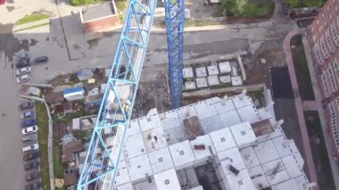 görüntüleri bir inşaat alanında bir yükseklikte bir çok katlı kırmızı tuğla yapılmış ev ve araba ile Park yerinde araçlarıyla gri beton monolith üzerinden bina üzerinde çalışan bir blue vinç ile.