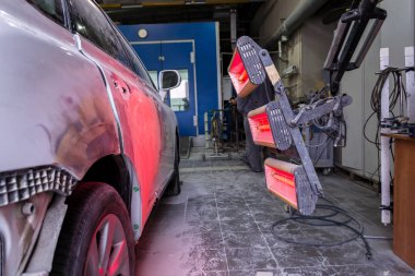 Kızılötesi araba vücut parçaları üzerinde bir beyaz off-road aracı vücut onarım dükkanda kırmızı fener çalışma ortamı ile macun ve boya uygulandıktan sonra kurutma