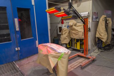 Kızılötesi radyatör ızgarası gibi araba vücut parçaları üzerinde tamircisi araca çalışma ortamı kırmızı fener ile macun ve boya uygulandıktan sonra kurutma