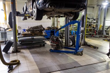 Bir spor araba Asansör onarıma ve altında üzerinde mavi bir vinç ve vites kutusu araç tamir dükkanı kaldırma tabloda askıya müstakil bir motoru kaldırdı