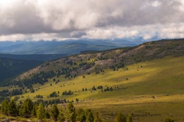 Yeşil vadi peyzaj yemyeşil yeşil çimen, ışıkla ile dağlar, kaplı taş ve hills, mavi gökyüzü beyaz bulutlar ve Altay Dağları'nda güneş ışınları altında bir taze yaz günü ile sular altında