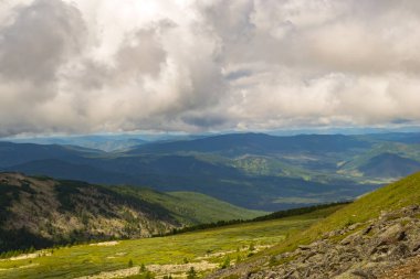 Yeşil vadi peyzaj yemyeşil yeşil çimen, ışıkla ile dağlar, kaplı taş ve hills, mavi gökyüzü beyaz bulutlar ve Altay Dağları'nda güneş ışınları altında bir taze yaz günü ile sular altında
