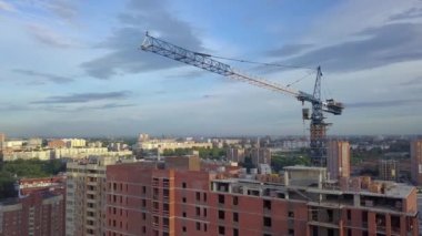 Yapım aşamasında bir mavi kule vinç, vinç, sonunda kırmızı fener ile yeni bir modern ev hava görünümünü İnşaat malzemeleri en üst kat, tuğla, çimento, mavi bir gökyüzü ve bulutlar karşı