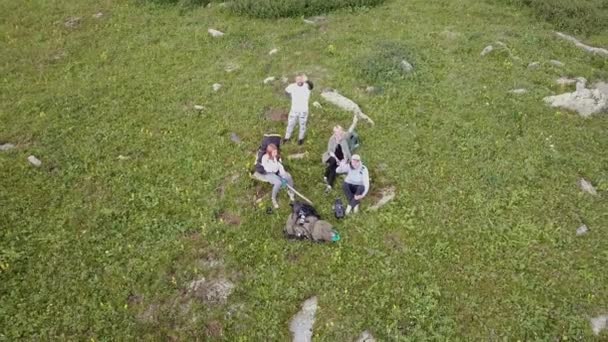 Čtyři Turisté Sedí Velké Zelené Glade Úpatí Vysokých Skalnatých Horských — Stock video