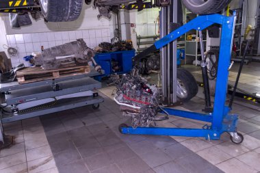 Bir spor araba Asansör onarıma ve altında üzerinde mavi bir vinç ve vites kutusu araç tamir dükkanı kaldırma tabloda askıya müstakil bir motoru kaldırdı