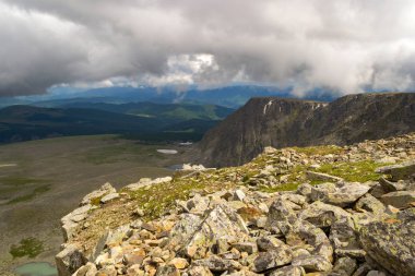 Altay Dağları tepesinden vadi yeşil çayırlar, orman, kar buzul taşlar ve kayalar birçok göl ile görüntüleyin. Gri bulutlar arasında güneşli bir sonbahar gününde güzel bir manzara