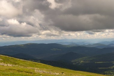 Yeşil vadi peyzaj yemyeşil yeşil çimen, ışıkla ile dağlar, kaplı taş ve hills, mavi gökyüzü beyaz bulutlar ve Altay Dağları'nda güneş ışınları altında bir taze yaz günü ile sular altında