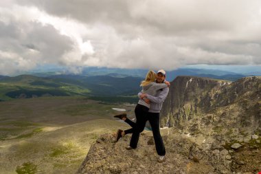 Sevgi dolu bir çift arka plan banyo güneş ışığı, tepeler, buzullar, kayalar kar ve beyaz bulutlar ile mavi göller bir vadinin sarılma dağda duruyor.