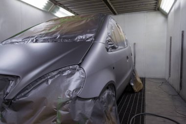 Gümüş bir arabanın arka koltuğunda olan bazı kısımları boya damlacıkları özel kutusunda ve ekipman ile bir araba vücut tamir dükkanında sıçramalarına kağıttan tarafından korunmaktadır bir hatchback tam resmini