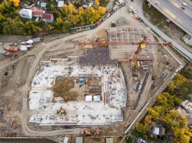 Elit İnşaat malzemeleri günbatımı sırasında sonbaharda bulutsuz bir günde bir depo ile üç büyük sarı vinçler ve gökdelen ile şehir merkezi bina bir hava üstten görünüm