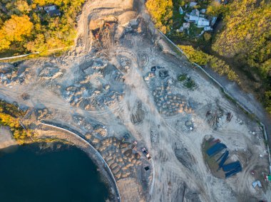 İnşaat alanında bir sondaj teçhizat, ekskavatör ve üç kamyon toprak ulaşım için yüklenmesini beklemek ile zemin hazırlanması ve inşaat ilk aşamada üstten görünüm