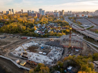 Bir inşaat alanında çok sayıda farklı kullanım araçları ve araç kamyon vinç ve ekskavatör sırasında işçilerin mavi gökyüzü altında bir sitede çalışma günü ile birlikte, havadan görünümü