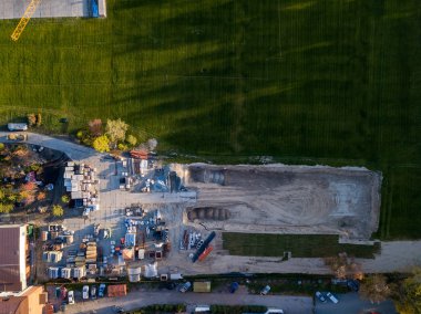 Bir bina inşaat havadan görünümü site İnşaat malzemeleri için moloz taşı ve tuğla çimento, sonbahar bir güneşli gün batımında yeşil çim çimen ile çevrili bir yerde