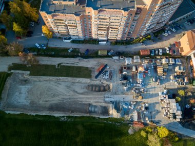 Bir bina inşaat havadan görünümü site İnşaat malzemeleri için moloz taşı ve tuğla çimento, sonbahar bir güneşli gün batımında yeşil çim çimen ile çevrili bir yerde