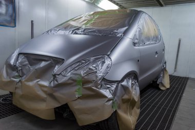 Gümüş bir arabanın arka koltuğunda olan bazı kısımları boya damlacıkları özel kutusunda ve ekipman ile bir araba vücut tamir dükkanında sıçramalarına kağıttan tarafından korunmaktadır bir hatchback tam resmini