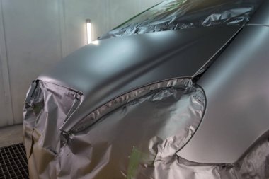 Gümüş bir arabanın arka koltuğunda olan bazı kısımları boya damlacıkları özel kutusunda ve ekipman ile bir araba vücut tamir dükkanında sıçramalarına kağıttan tarafından korunmaktadır bir hatchback tam resmini