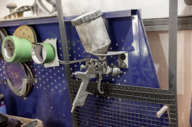 Mavi bir tezgah başka bir aracının yanındaki araç tamir atölyesinde yüklü vücut boya püskürtme