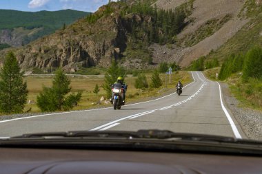 Bir toplantı için bir serpantin Altay Dağları'nda yüksek hızda yarış sırasında seyahat eden iki spor motosiklet için arabanın penceresinden görüntülemek