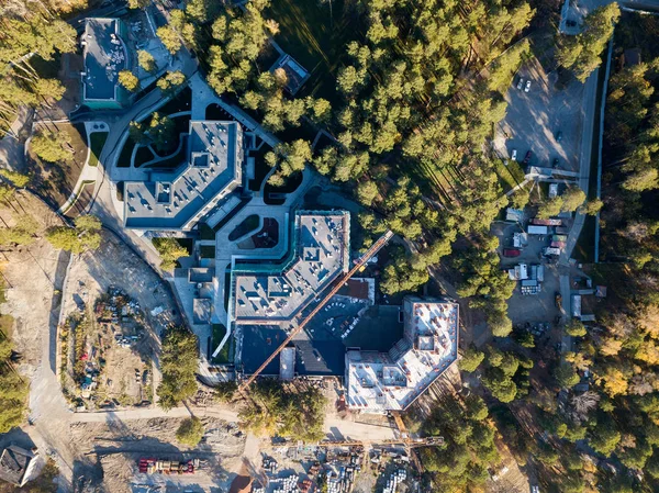 Aerial view of the construction of three elite residential buildings on the river bank in the middle of a green coniferous forest with a favorable environment, a lot of equipment costs near the site