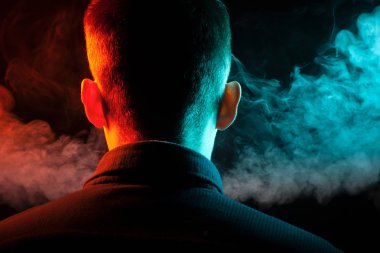 Bir vape sigara ve çok renkli duman yeşil ve kırmızı farklı yönden kendini izole bir siyah arka plan üzerine adlı parçasıyla birlikte kullanılmalıdır gömlekli bir adam kafasına arkadan görünüm
