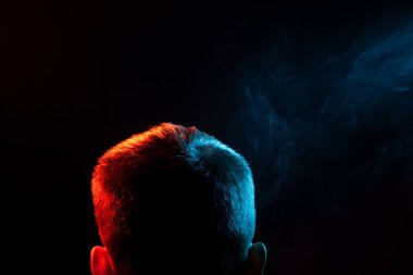Bir vape sigara ve exhaling gömlekli bir insan kafası arkasında bir görünümden farklı yönden kendini bir siyah, yeşilin çok renkli duman izole arka plan. İnsan ruhu ve düşüncelerini.