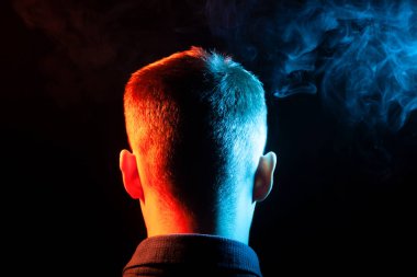 Bir vape sigara ve çok renkli duman yeşil ve kırmızı farklı yönden kendini izole bir siyah arka plan üzerine adlı parçasıyla birlikte kullanılmalıdır gömlekli bir insan kafası arkasında bir manzara. İnsanın ruh ve düşüncelerini.