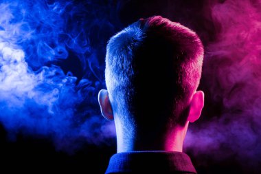 Bir vape sigara ve çok renkli duman mavi ve kırmızı farklı yönden kendini izole bir siyah arka plan üzerine adlı parçasıyla birlikte kullanılmalıdır gömlekli bir adam kafasına arkadan görünüm