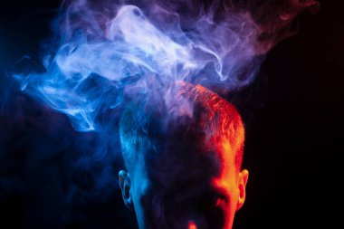 Gölge ve kafa bir adamın yüzü bir vape dumanlar ve çok renkli duman mavi ve pembe onun başının üstünde dışarı onun sağlık zarar verir kırmızı vurgulanır. Düşünce ve ruh.