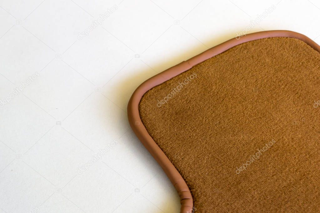 A part of a handmade brown rug made from natural wool with leather trim for car passengers in an interior workshop