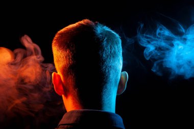 Bir vape sigara ve çok renkli duman mavi ve kırmızı farklı yönden kendini izole bir siyah arka plan üzerine adlı parçasıyla birlikte kullanılmalıdır gömlekli bir çocuğun kafasına arkadan görünüm
