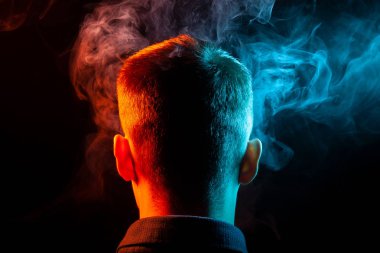 Bir vape sigara ve çok renkli duman mavi ve kırmızı farklı yönden kendini izole bir siyah arka plan üzerine adlı parçasıyla birlikte kullanılmalıdır gömlekli bir çocuğun kafasına arkadan görünüm