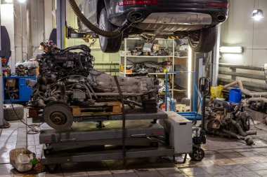 Bir Suv araç tamir için ve altında bir asansör üzerinde ışıklar bir sürü araç tamir atölyesinde tablo kaldırma bir gri askıya müstakil bir motoru kaldırdı