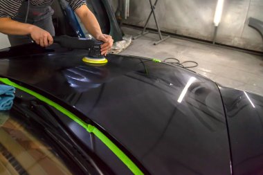 Atölye ayrıntılı bir araç çalışırken bir arabanın kaputuna parlatma için bir araç tutan bir erkek işçinin ellerinde yakından görmek.