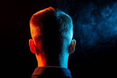 Bir vape sigara ve çok renkli duman yeşil ve kırmızı farklı yönden kendini izole bir siyah arka plan üzerine adlı parçasıyla birlikte kullanılmalıdır gömlekli bir çocuğun kafasına arkadan görünüm