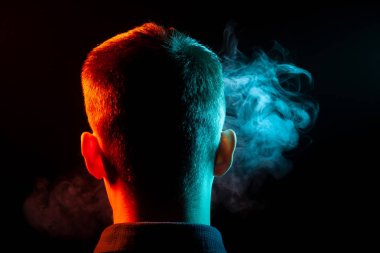 Bir vape sigara ve çok renkli duman yeşil ve kırmızı farklı yönden kendini izole bir siyah arka plan üzerine adlı parçasıyla birlikte kullanılmalıdır gömlekli bir adam kafasına arkadan görünüm