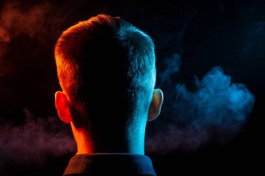 Bir vape sigara ve çok renkli duman yeşil ve kırmızı farklı yönden kendini izole bir siyah arka plan üzerine adlı parçasıyla birlikte kullanılmalıdır bir gömlekli bir adam kafasına arkadan görünüm