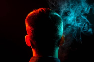 Bir vape sigara ve çok renkli duman yeşil ve kırmızı farklı yönden kendini izole bir siyah arka plan üzerine adlı parçasıyla birlikte kullanılmalıdır gömlekli bir çocuğun kafasına arkadan görünüm