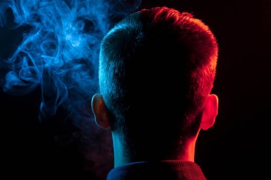Bir vape sigara ve çok renkli duman mavi ve kırmızı farklı yönden kendini izole bir siyah arka plan üzerine adlı parçasıyla birlikte kullanılmalıdır gömlekli bir adam kafasına arkadan görünüm