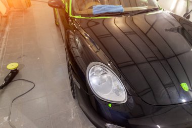 Bakım ve yıkama, çizikler, polisaj ve zımpara makinesi, yakın çekim kaput çamurluk ve far kullanarak araç gövdesi gizleme balmumu ile kaplı sonrası istasyonunda siyah bir araba bakım.