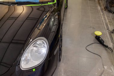 Boyama, yıkama ve kaput çamurluk ve farlar, araç su birikintileri yerde çizikler gizler bir cilalama makinesi kullanarak profesyonel balmumu ile kaplama sonra kutusunda siyah temiz araba.