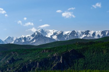 Tepelerin Vadisi'nin güzel manzara ile yeşil otlar ve ağaçlar karla kaplı tepeler taş ridge önünde üzerinde beyaz buz mavi gökyüzü altında yatıyor kapalı.