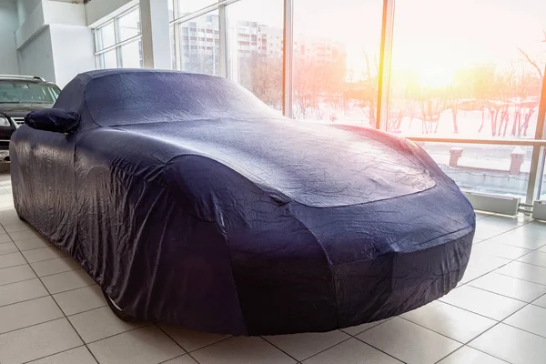 The expensive car in the box is carefully prepared for winter operation, covered with a professional cover made of blue special fabric, custom-made, perfectly suitable for all elements of the body.