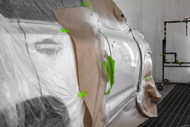 Beyaz araba Suv için vücut onarım atölye boyama. Araba kağıt ile kaplı ve boya isabet örtmek.