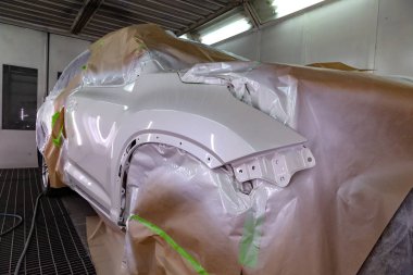 Beyaz araba Suv için vücut onarım atölye boyama. Araba kağıt ile kaplı ve boya isabet örtmek.