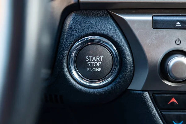 Button start and turn off the ignition of the car engine close-up on the dashboard, electric key, pressing drives the motor vehicle of modern design.