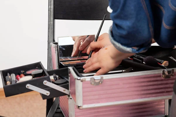 A set of professional cosmetics in the beauty case of a make-up artist in the open form. Make-up artist the girl at work in the studio of visage the shadows a brush from a politra.