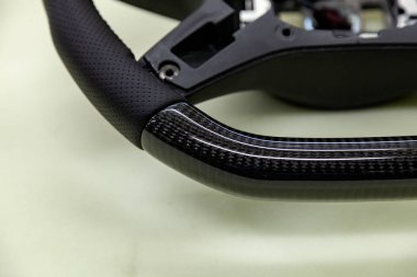 Araba iç detay öğesidir bir olağandışı karbon direksiyon mor iplikle bir oto tamir atölyesi'nde yakın çekim hakiki siyah deri ile dikişli.