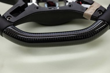 Araba iç detay öğesidir bir olağandışı karbon direksiyon mor iplikle bir oto tamir atölyesi'nde yakın çekim hakiki siyah deri ile dikişli.