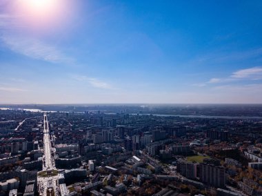Manzara nehir, çok katlı binalar, ana yol, yeşil ağaçlar ve bir hava ve mavi gökyüzü bulutlar ile bir yaz gününde bir güneş olmadan demir rooftops evlerden şehrin.